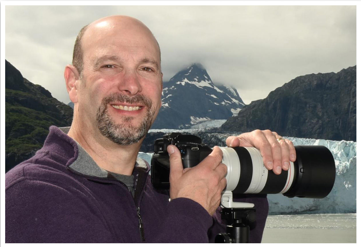 Portrait of Brad Balfour holding a camera in studio lighting