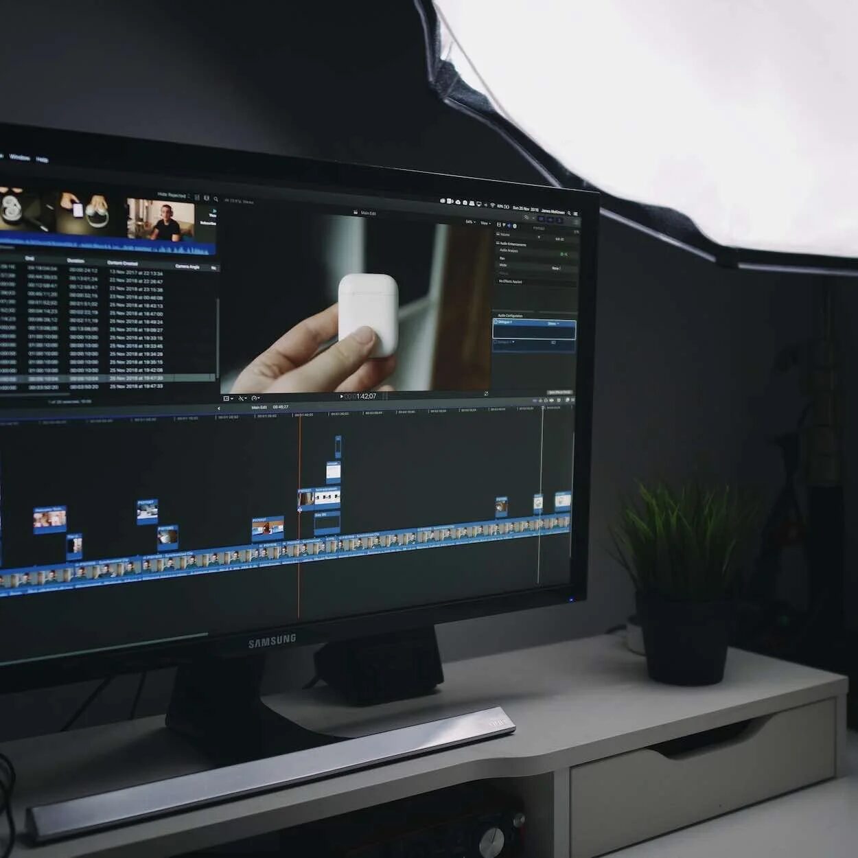 Video editor working at a desk with multiple monitors and control surface
